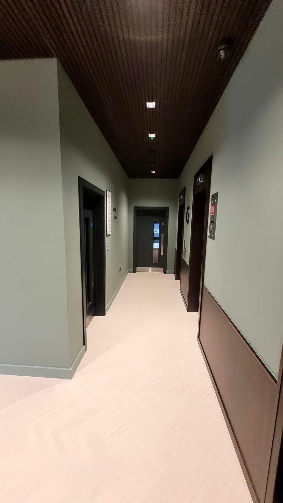 Commercial hallway decorated with sage green walls and dark panelling